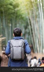 Young man Traveling at Arashiyama Bamboo Grove, Happy Asian traveler looking Sagano Bamboo Forest. landmark and popular for tourists attractions in Kyoto, Japan. Asia travel concept