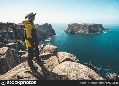 Young man trekker hiking on beautiful coast cliff of Tasman National Park in Tasman peninsula, Three Capes Track near Port Arthur in Tasmania, Australia.