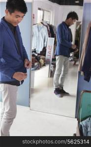 Young man trying on jacket at fashion store