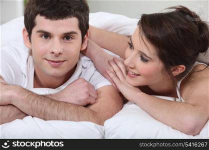 young man turned toward camera with girlfriend in bed