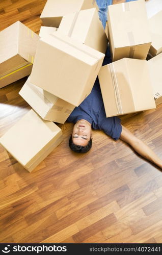 Young man under a pile of boxes