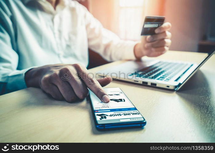 Young man use credit card for shopping payment online on laptop computer application or website. E-commerce and online shopping concept.