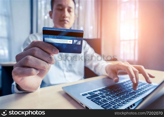 Young man use credit card for shopping payment online on laptop computer application or website. E-commerce and online shopping concept.