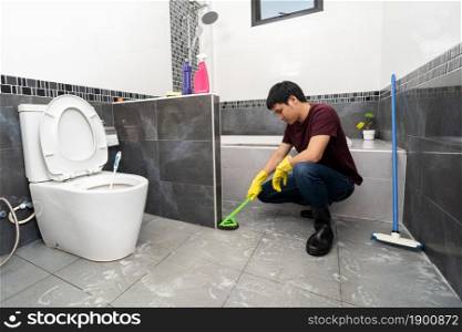 young man using brush to cleaning the tile in the bathroom