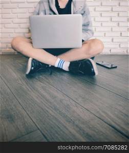 Young man using laptop and sitting on the floor in the cafe or home