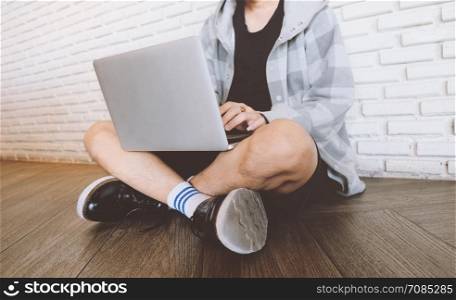 Young man using laptop and sitting on the floor in the cafe or home