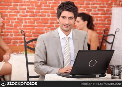 Young man using laptop in a restaurant
