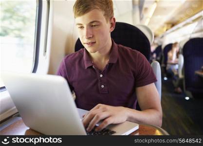 Young Man Using Laptop On Train Journey