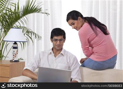 Young man using laptop while woman looking