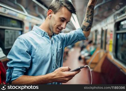 Young man using phone in metro, addiction problem, social addicted people, modern underground lifestyle. Young man using phone in metro, addicted people