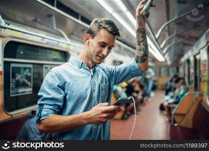 Young man using phone in metro, addiction problem, social addicted people, modern underground lifestyle