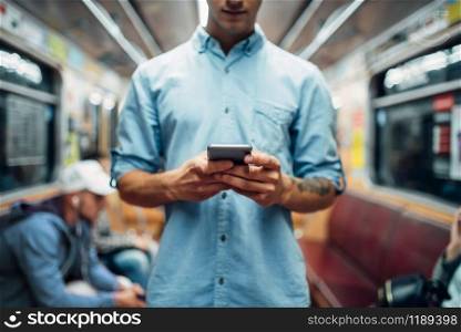 Young man using phone in subway car, addiction problem, social addicted people, modern underground lifestyle. Man using phone in subway car, addicted people