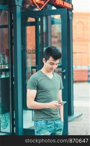 Young man using smartphone standing in center of town