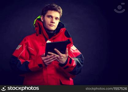 Young man using tablet. Male in windproof waterproof clothing. Internet connection adventure danger outdoors concept. . Young man using tablet
