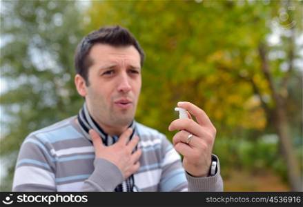 Young man using throat spray in cold season