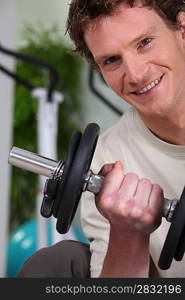 Young man using weights in a gym