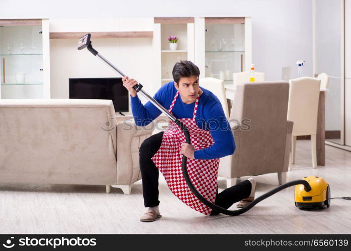 Young man vacuum cleaning his apartment