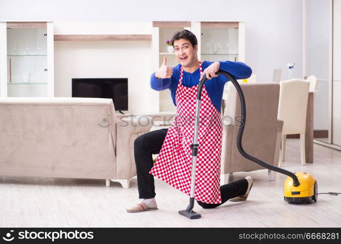 Young man vacuum cleaning his apartment