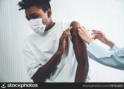 Young man visits skillful doctor at hospital for vaccination . Covid 19 and coronavirus vaccination center service concept .. Young man visits skillful doctor at hospital for vaccination