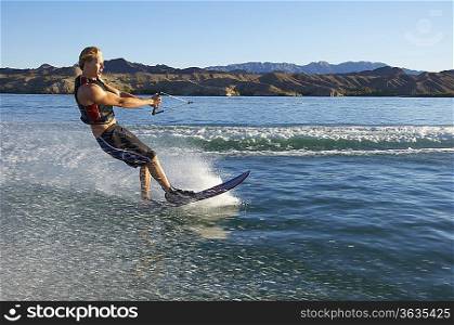 Young man wakeboarding on lake