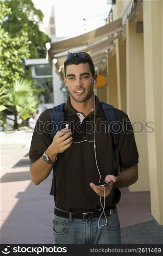 Young man walking and listening to an MP3 player