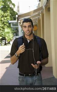 Young man walking and listening to an MP3 player