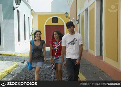 Young man walking with two young women on a cobblestone street, Old San Juan, San Juan, Puerto Rico