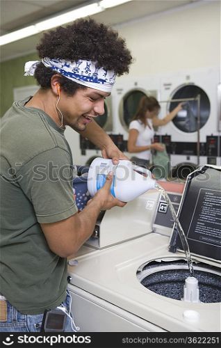 Young man washing clothes at launderette