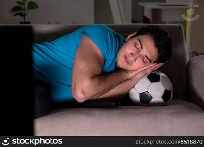 Young man watching football late at night