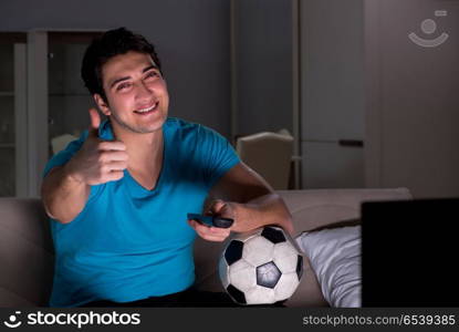 Young man watching football late at night