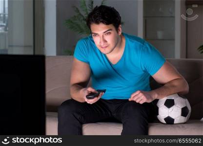 Young man watching football late at night