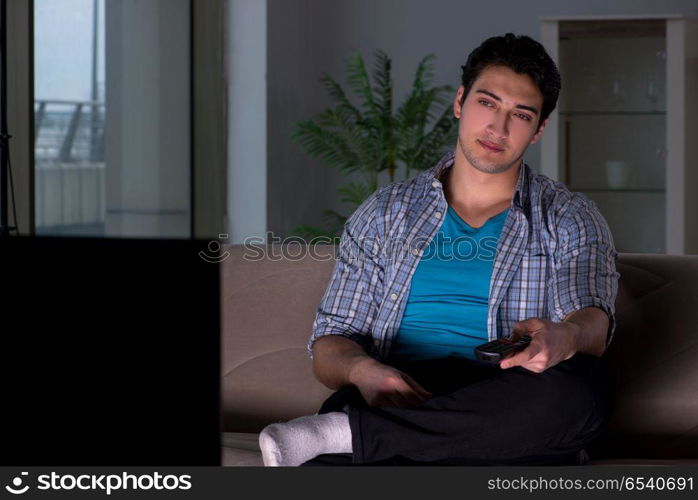 Young man watching tv late at night