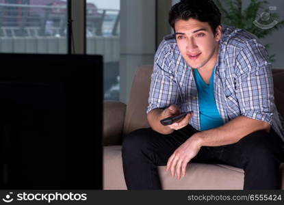 Young man watching tv late at night