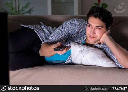 Young man watching tv late at night