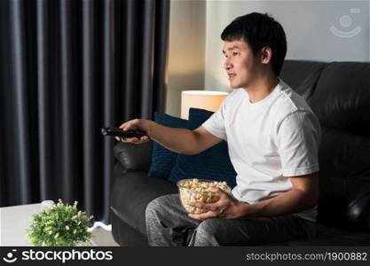 young man watching TV on sofa at night