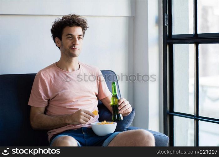 Young man watching tv on the couch, fan celebrating goal. Sports and entertainment concept.