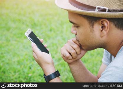 Young Man wear hat sit using mobile smart phone.