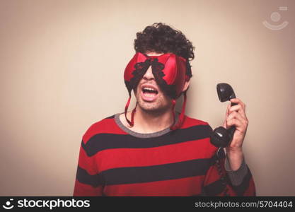 Young man wearing a bra on his face is holding a telephone receiver
