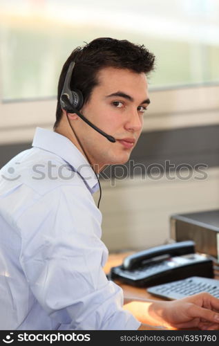 Young man wearing a headset in front of a computer