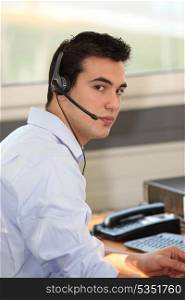 Young man wearing a headset in front of a computer