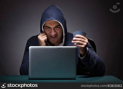 Young man wearing a hoodie sitting in front of a laptop computer. Young man wearing a hoodie sitting in front of a laptop computer gambling