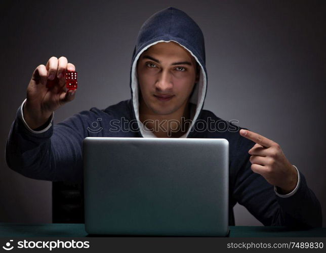 Young man wearing a hoodie sitting in front of a laptop computer gambling. Young man wearing a hoodie sitting in front of a laptop computer