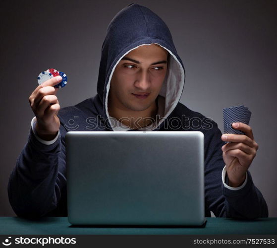 Young man wearing a hoodie sitting in front of a laptop computer gambling. Young man wearing a hoodie sitting in front of a laptop computer