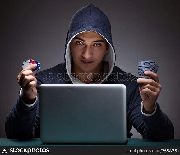 Young man wearing a hoodie sitting in front of a laptop computer gambling. Young man wearing a hoodie sitting in front of a laptop computer