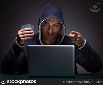 Young man wearing a hoodie sitting in front of a laptop computer gambling. Young man wearing a hoodie sitting in front of a laptop computer