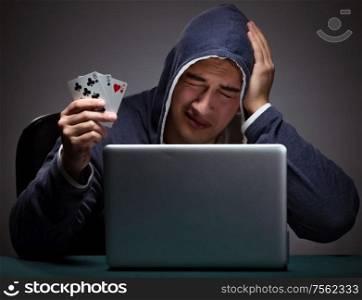 Young man wearing a hoodie sitting in front of a laptop computer gambling. Young man wearing a hoodie sitting in front of a laptop computer
