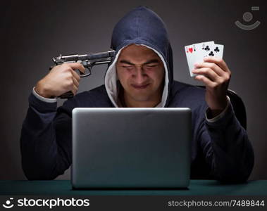 Young man wearing a hoodie sitting in front of a laptop computer gambling committing suicide. Young man wearing a hoodie sitting in front of a laptop computer