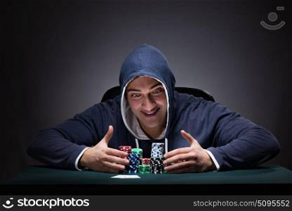 Young man wearing a hoodie with cards and chips gambling