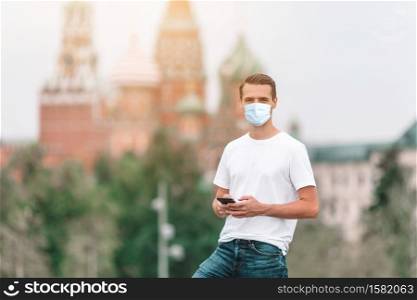 Young man wearing a mask for prevent virus outdoors on background of St Basils Church. Portrait of businessman in big city. Protection against Coronavirus and gripp. Happy young urban man in european city.