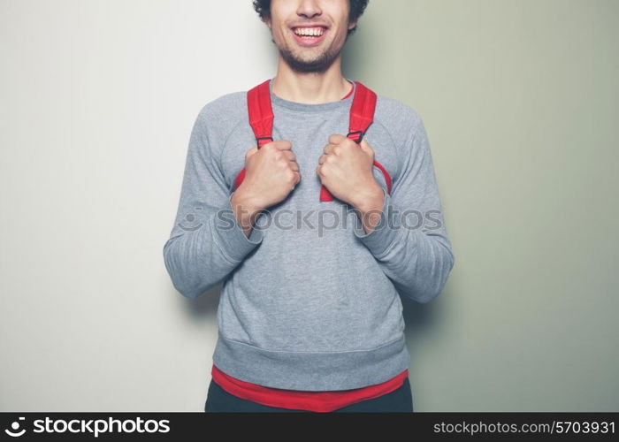 Young man wearing a red backpack is standing against a green and white background